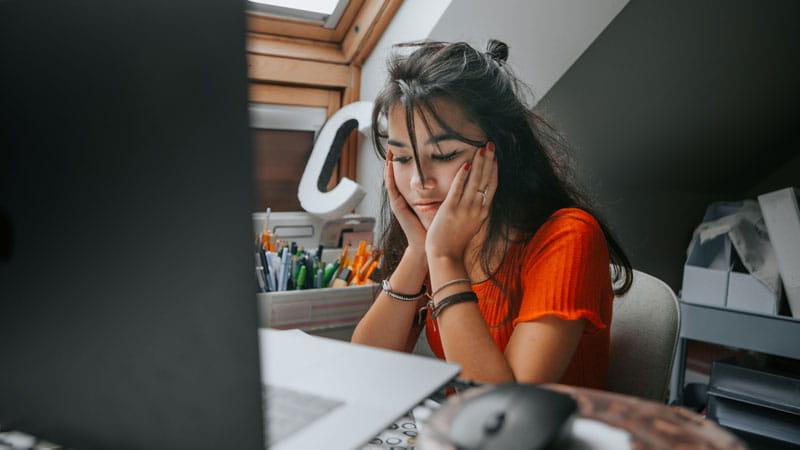 female teenager feeling stressed studying at home