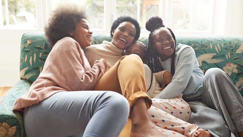 Portrait of happy woman embracing girls at home