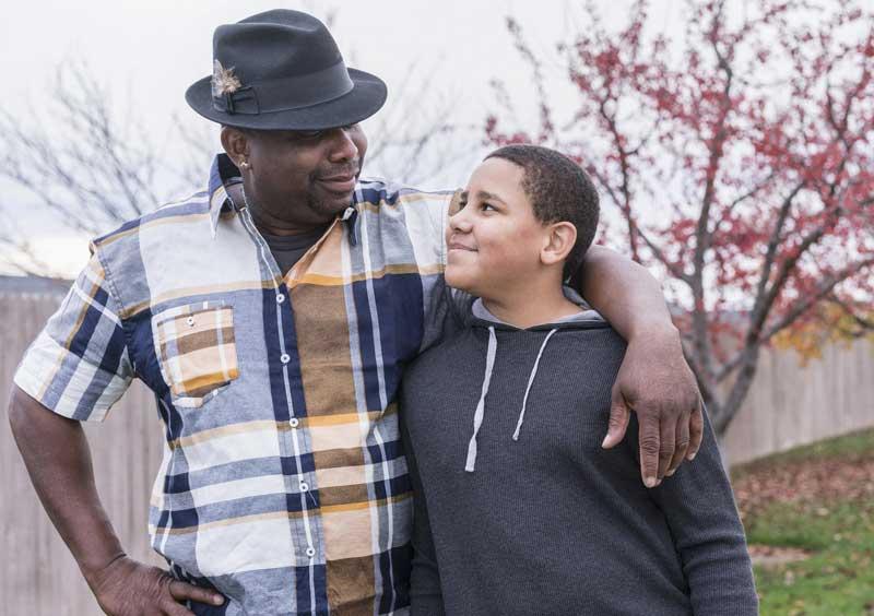 Black man and son arm in arm