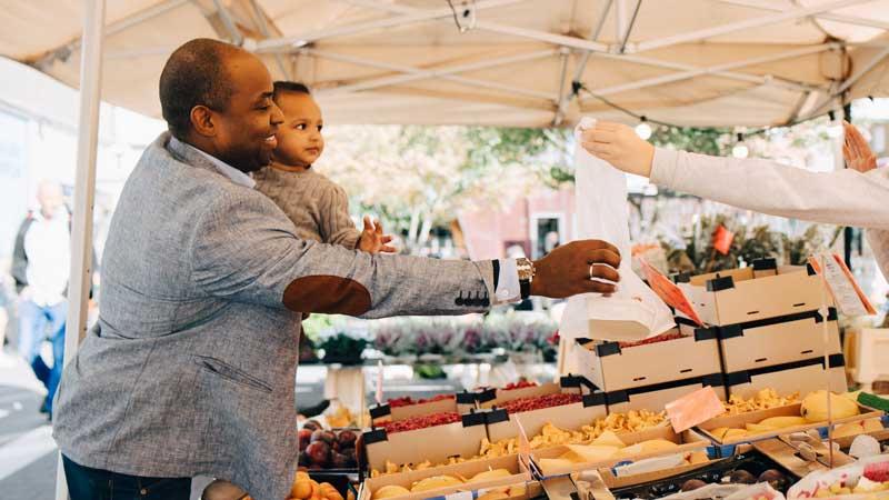 man and child buying veggies at farmers market