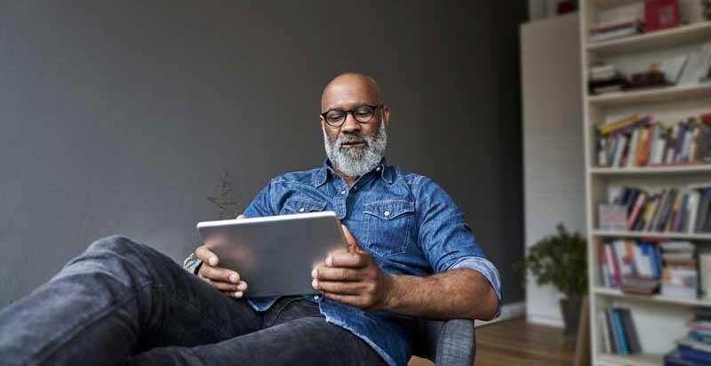 man reclining in chair reading tablet