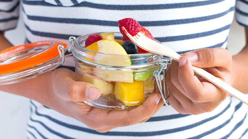 Person with a jar of assorted fruit 