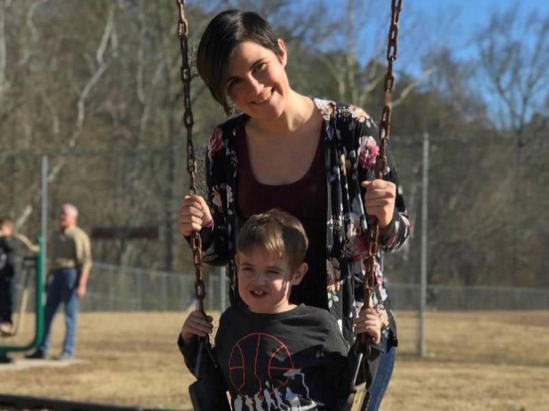 Bennett Sayles, who has survived five open-heart surgeries, smiles on a playground with his mom, Hannah Lewis. (Photo courtesy of Hannah Lewis)